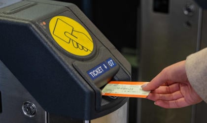 A passenger inserting a ticket in to a barrier. 