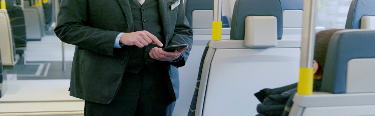 A ticket inspector speaking to a passenger on a train. 